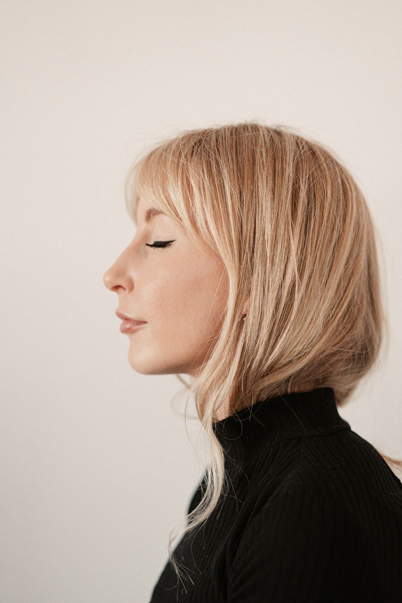 Perfil de mulher com pele luminosa e olhos fechados, sobre fundo claro